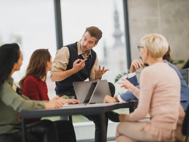Vier Personen besprechen Unterlagen an einem Konferenztisch.