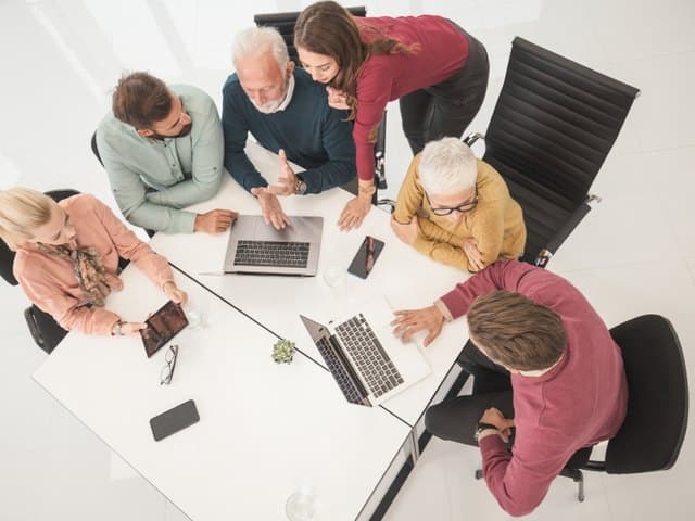 Team arbeitet von oben gesehen gemeinsam an Laptops.